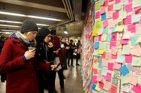 People leave post-its on the wall of a subway station expressing disapproval after 2016 Election