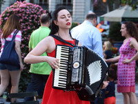 A young woman singing and playing an accordion in Bryant Park