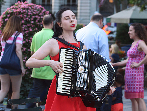 A young woman singing and playing an accordion in Bryant Park