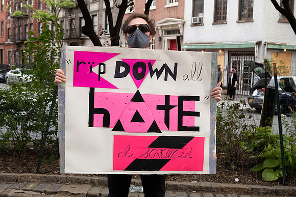 A man holding up a sign at a protest against hate and police violence in Greenwich Village